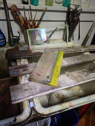 Squegee placed on drying boards over an ink-stained sink.